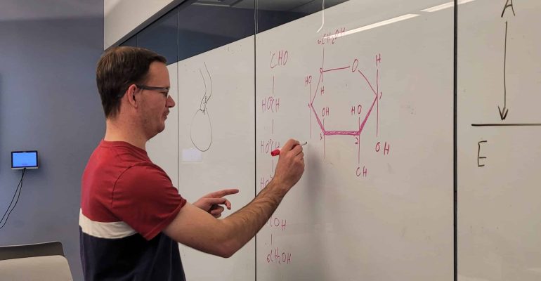 Biology student writing on whiteboard